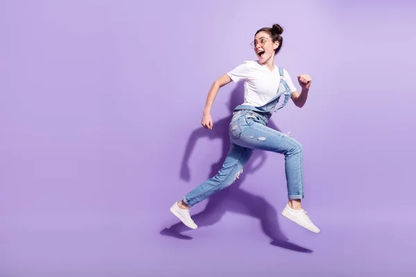 Повний розмір профілю фотографія молодої збудженої дівчини щаслива посмішка стрибок йти бігати поспішати ізольовано на фіолетовому кольоровому фоні — стокове фото