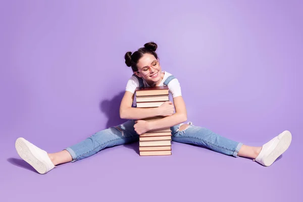 Foto av söt drömmande ung dam bära jeans övergripande sittande golv omfamna böcker isolerad violett färg bakgrund — Stockfoto