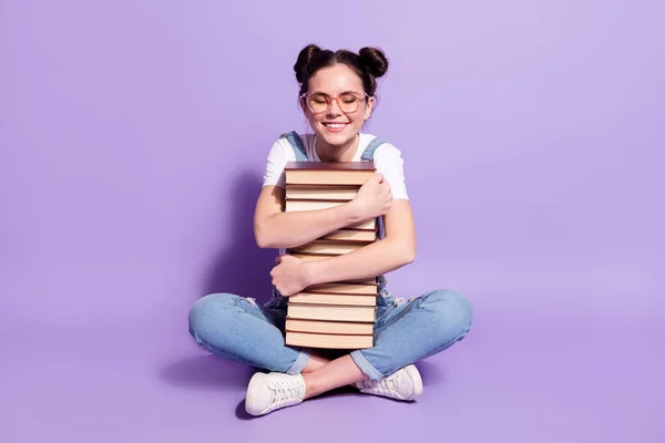 Full body photo of young excited girl happy positive smile sit floor hug books isolated over violet color background — Stock Photo, Image