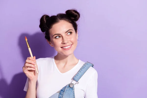 Ritratto di affascinante positivo braccio giovane ragazza tenere pennello guardare lo spazio vuoto isolato su sfondo di colore viola — Foto Stock