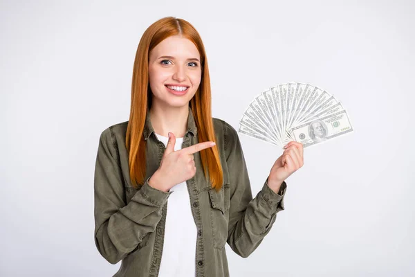 Foto de bom humor feliz sorrindo linda mulher bonita apontar dedo em dinheiro dólares isolados em fundo de cor cinza — Fotografia de Stock