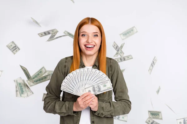 Retrato de menina de cabelos vermelhos alegre atraente segurando salário em dinheiro freelance voando resíduos isolados sobre fundo de cor de luz branca — Fotografia de Stock