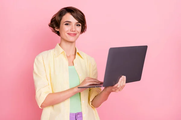 Foto de brilhante muito jovem mulher usar camisa amarela segurando dispositivo moderno isolado cor de fundo rosa — Fotografia de Stock