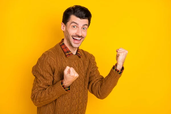 Foto van opgewonden jonge man verhogen vuisten open mond slijtage bruin trui geïsoleerde helder gele achtergrond — Stockfoto