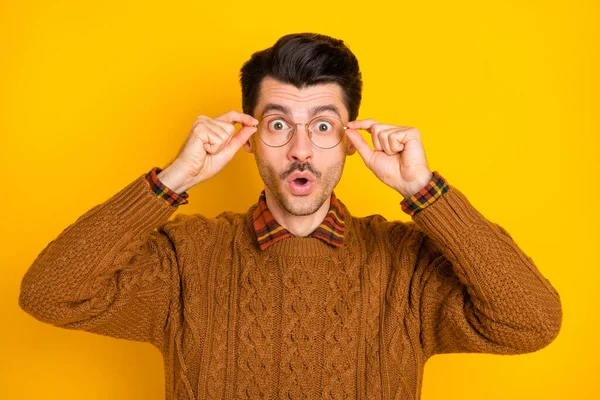 Foto von erstaunt jungen Kerl halten Brille offenen Mund tragen braunen Pullover isoliert lebendigen gelben Hintergrund — Stockfoto