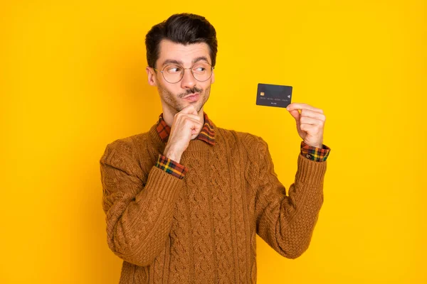 Foto van minded attent man look houden plastic creditcard hand kin geïsoleerd op gele kleur achtergrond — Stockfoto