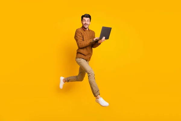 Full size zdjęcie profilu pod wrażeniem ładne brunet człowiek trzymać laptop nosić sweter izolowany na żółtym tle — Zdjęcie stockowe