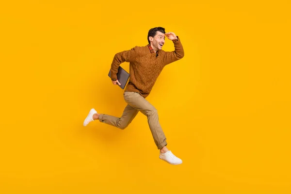 Full storlek profil foto av imponerad trevlig brunett man hålla bärbar dator springa slitage tröja isolerad på gul bakgrund — Stockfoto