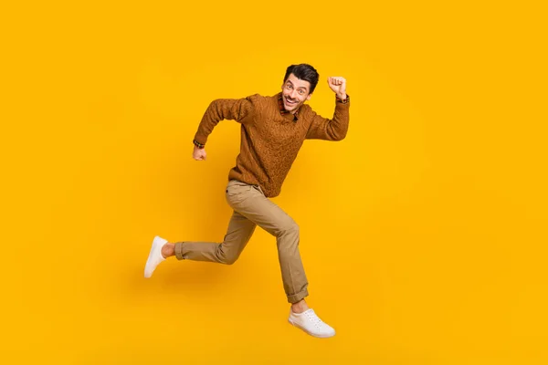 Pełnowymiarowe zdjęcie profilowe optymistycznego człowieka brunet biegać nosić sweter izolowany na żółtym tle — Zdjęcie stockowe