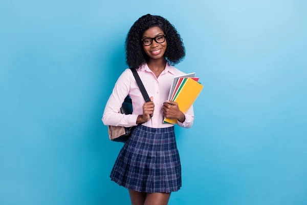 Afrikalı genç bir kızın fotoğrafı mutlu bir gülümseme içinde not defterlerini mavi arkaplanda saklayın. — Stok fotoğraf