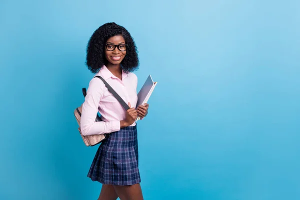 Profilo foto laterale di giovane ragazza della scuola africana felice sorriso positivo tenere quaderni compiti isolati su sfondo di colore blu — Foto Stock