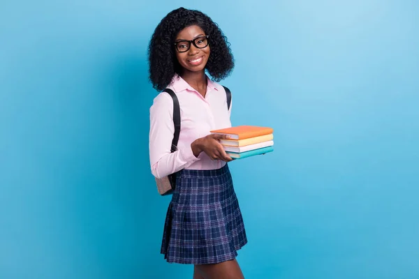 Profilo foto laterale di giovane allegra ragazza della scuola africana tenere libri studio compiti isolati su sfondo di colore blu — Foto Stock