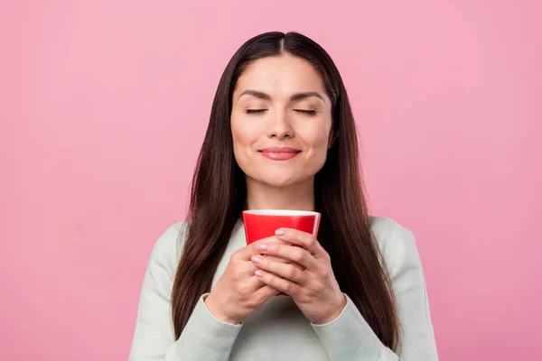 Фото спокойной мечтательной молодой женщины держаться за руки запах кофе чашку хорошее настроение изолированы на розовом фоне цвета — стоковое фото