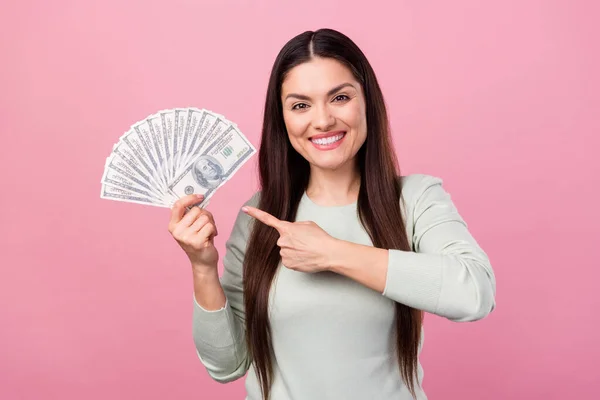 Foto de atraente feliz positivo mulher madura apontar dedo dinheiro lucro salário isolado no fundo cor-de-rosa — Fotografia de Stock