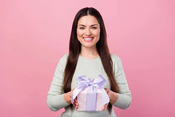Foto de encantadora mujer joven atractiva cogida de la mano caja de regalo sonrisa buen humor aislado en el fondo de color rosa —  Fotos de Stock