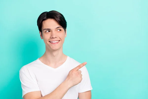 Foto von lustigen brünetten Frisur Teenager Kerl Punkt suchen leeren Raum tragen weißes T-Shirt isoliert auf lebendigen teal Farbhintergrund — Stockfoto