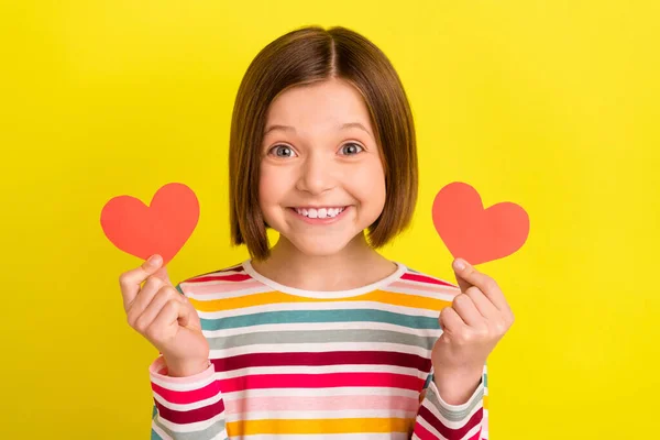 Foto retrato menina mostrando dois pequenos cartões postais do coração sorrindo isolado cor amarela brilhante fundo — Fotografia de Stock