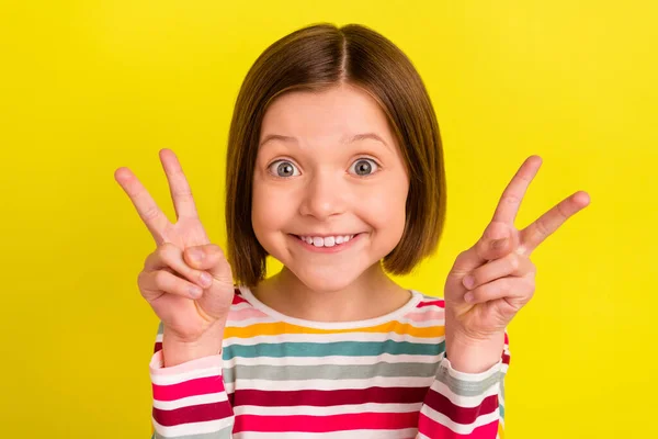 Φωτογραφία πορτρέτο κοριτσάκι δείχνει V-σημάδι χειρονομία και τα δύο χέρια χαμογελώντας απομονωμένο φωτεινό κίτρινο χρώμα φόντο — Φωτογραφία Αρχείου