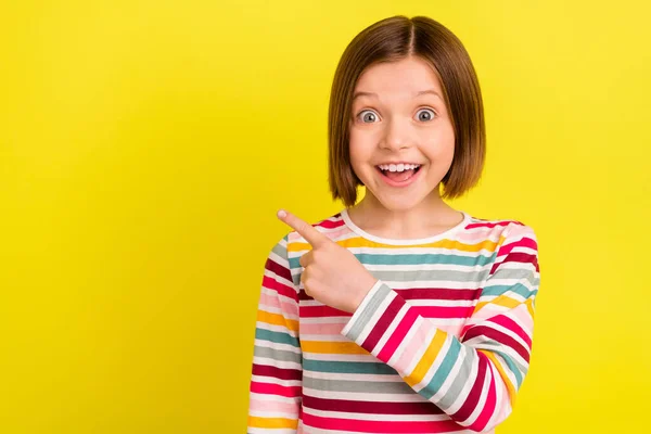 Foto retrato menina vestindo camisa listrada apontando aconselhando copyspace chocado olhando isolado vívido cor amarela fundo — Fotografia de Stock