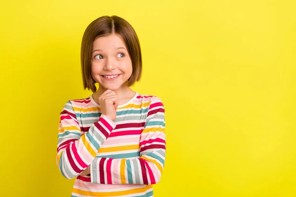 Foto von glücklich fröhlich nett gesinnte kleine Mädchen suchen leeren Raum halten Hand Kinn isoliert auf gelbem Hintergrund — Stockfoto