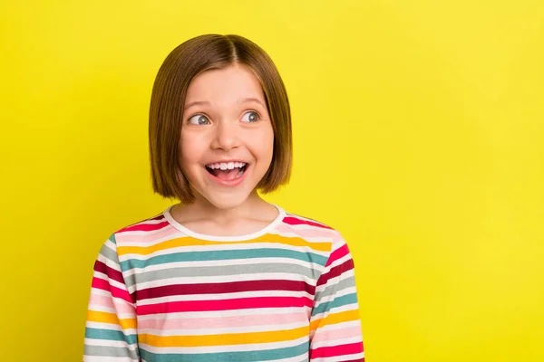 Foto von fröhlich erstaunt kleine Mädchen sehen leeren Raum gute Laune Lächeln isoliert auf gelbem Hintergrund — Stockfoto