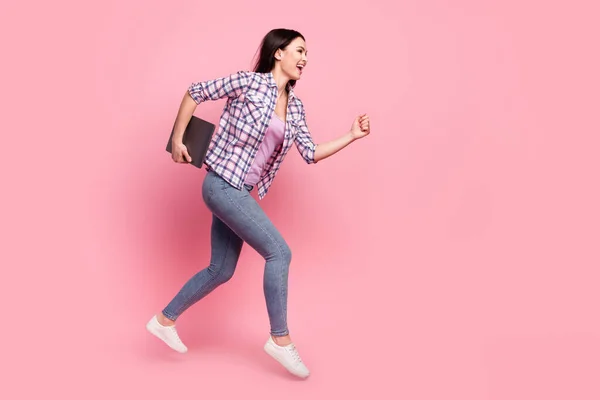 Foto de cuerpo entero de mujer joven bastante brillante usar camisa a cuadros saltando sosteniendo dispositivo moderno espacio vacío aislado color rosa fondo —  Fotos de Stock