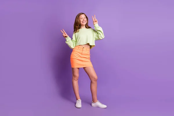 Foto in voller Länge von jungen fröhlichen Mädchen glücklich positives Lächeln zeigen Frieden cool V-Zeichen isoliert über violette Farbe Hintergrund — Stockfoto