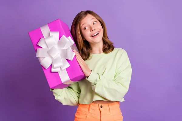 Foto av ung skola flicka glad positiv leende skaka nyfiken present box födelsedag isolerad över violett färg bakgrund — Stockfoto