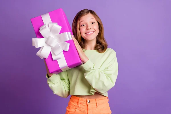 Fotografie mladé veselá dívka šťastný pozitivní úsměv držet dárek box strana dovolená izolované přes fialové barvy pozadí — Stock fotografie