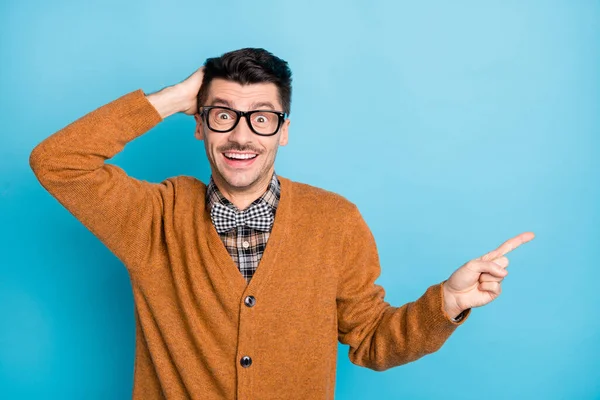 Foto van verbaasd man wijs vinger lege ruimte houden hand hoofd slijtage bril geïsoleerd op blauwe kleur achtergrond — Stockfoto