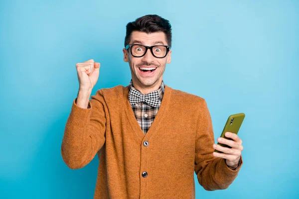 Foto di elegante uomo vittorioso sollevare pugno fortunato vincere tenere smartphone isolato su sfondo di colore blu — Foto Stock