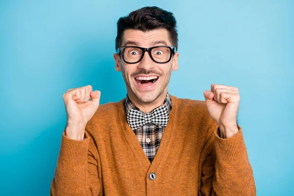 Foto de jovem animado homem feliz sorriso positivo comemorar punhos vitória vitória mãos isoladas sobre fundo de cor azul — Fotografia de Stock