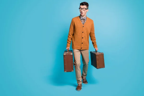 Full size photo of young man amazed shocked surprised go hold suitcase look empty space isolated over blue color background — стоковое фото