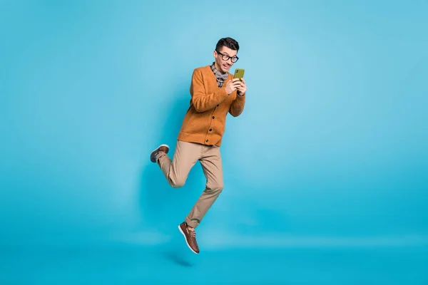 Πλήρης φωτογραφία μεγέθους του νεαρού άνδρα κατάπληκτος άλμα μέχρι τύπου συνομιλίας sms κινητό τηλέφωνο απομονωμένο πάνω από το μπλε φόντο χρώμα — Φωτογραφία Αρχείου