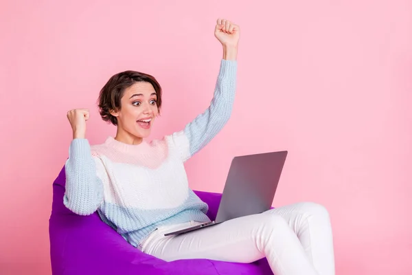 Profile photo of delighted person sitting soft chair look laptop fists up celebrate isolated on pink color background