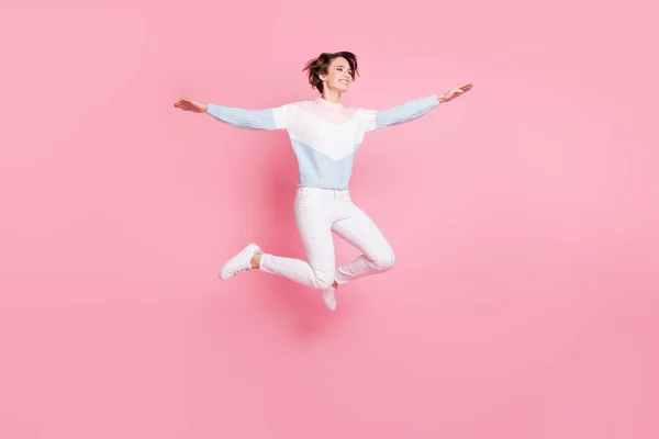 Lunghezza completa foto di divertente spensierata giovane signora vestita pullover saltare braccia alte lati isolato colore rosa sfondo — Foto Stock