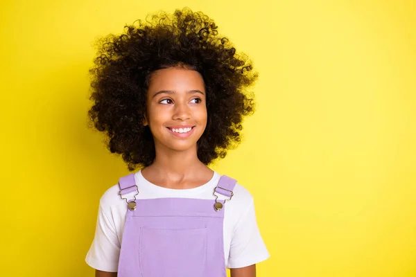 Портрет оптимістичної милої кучерявої дівчини в білій футболці виглядає порожнім простором ізольовано на жовтому кольорі — стокове фото
