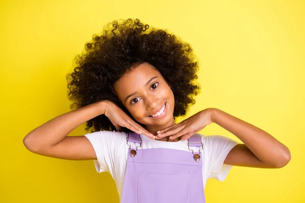 Фото очаровательной маленькой девочки ладони лицо сияющая улыбка смотреть камеры носить фиолетовый общий изолированный желтый цвет фона — стоковое фото