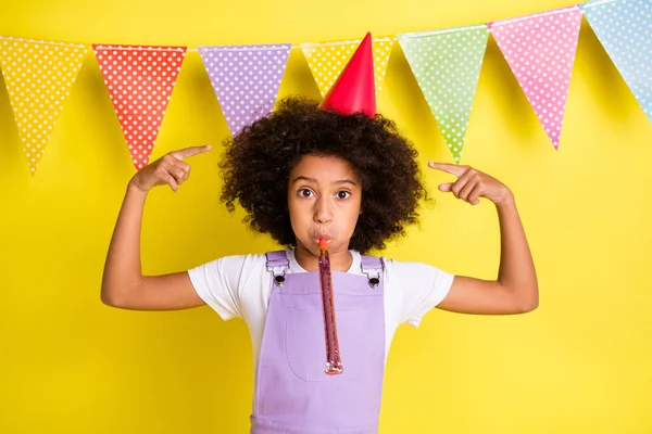 Foto van optimistisch schattig krullend meisje punt zelf spelen pijp slijtage hoed t-shirt geïsoleerd op gele kleur achtergrond — Stockfoto