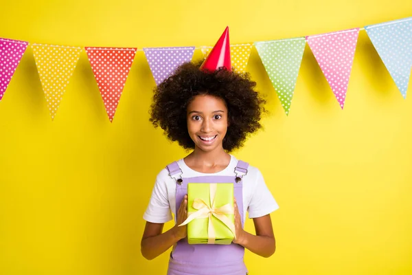 Foto di eccitato piccola ragazza tenere scatola regalo indossare tappo cono viola generale isolato colore giallo sfondo — Foto Stock