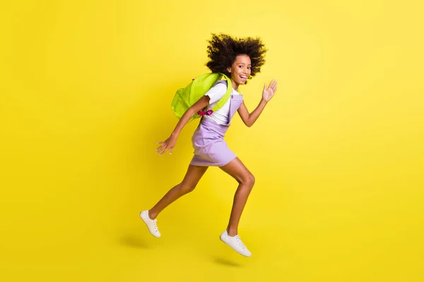 Longitud completa tamaño del cuerpo perfil vista lateral de alegre activa chica de pelo ondulado saltando corriendo aislado sobre fondo de color amarillo vivo — Foto de Stock