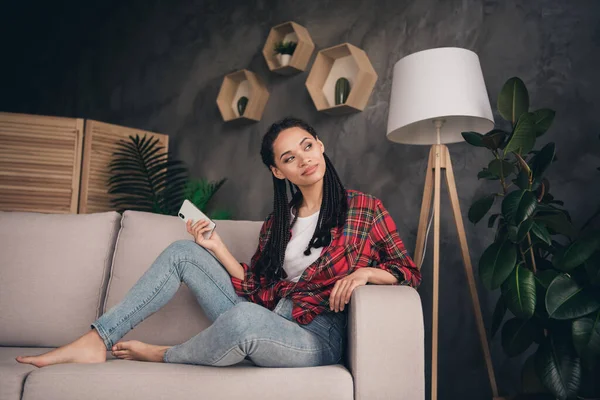 Portret van aantrekkelijk minded meisje zitten op de bank met behulp van gadget bloggen vrije tijd op moderne loft industriële flat house binnen — Stockfoto