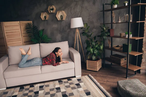 Portret van een aantrekkelijk dromerig meisje op blote voeten op de bank vrije tijd alleen op moderne loft industriële flat huis open ruimte huis binnen — Stockfoto