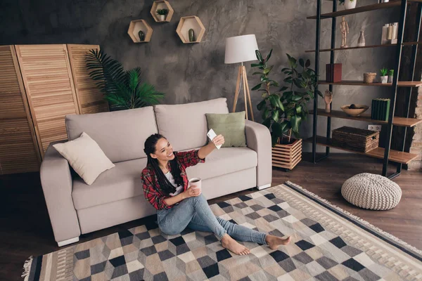 Retrato de una atractiva chica alegre sentada en el suelo bebiendo cafeína descansando tomando selfie blogging en el moderno loft industrial home interior — Foto de Stock