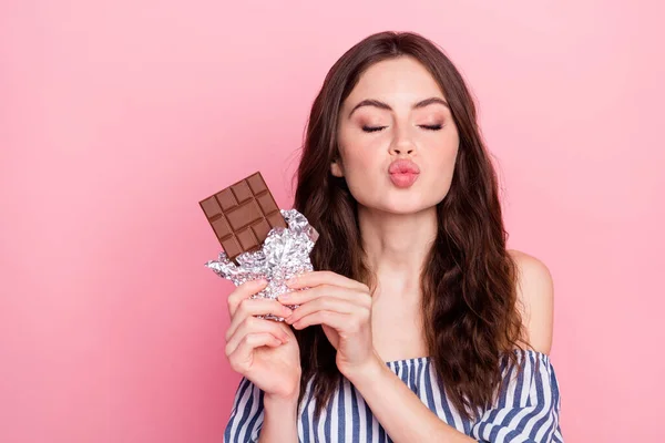 Foto van mooie optimistische brunette dame houden chocolade blow kiss slijtage blauwe jurk geïsoleerd op roze kleur achtergrond — Stockfoto