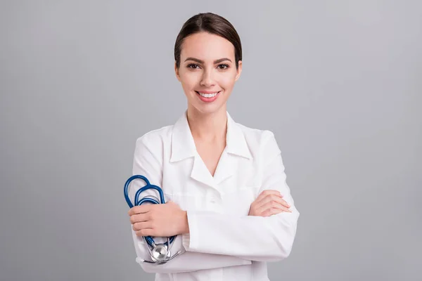 Kadın doktor, beyaz önlükle gülümseyen bir sthethoscope tutuyor. Gri arka plan. — Stok fotoğraf