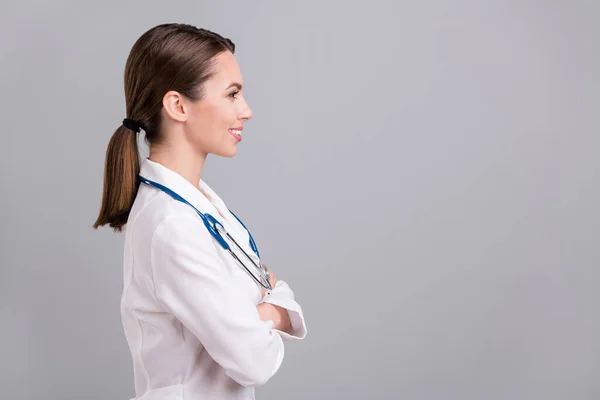 Zdjęcie dość słodki doktorek kobieta ubrana biały płaszcz uśmiechnięte ramiona skrzyżowane patrząc puste miejsce odizolowany szary kolor tła — Zdjęcie stockowe