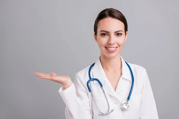 Zdjęcie portret kobieta lekarz z stetoskopem pokazując puste miejsce na dłoni odizolowany szary kolor tła — Zdjęcie stockowe