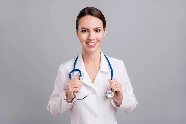 Фото чарівної солодкої молодої леді лікар робочого одягу руки фонендоскоп усміхнений ізольований сірий кольоровий фон — стокове фото