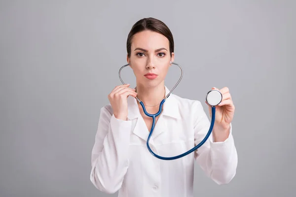 Zdjęcie poważnej, pewnej siebie młodej doktorki ubranej w biały płaszcz słuchającej oddechu odizolowanego szarego tła — Zdjęcie stockowe